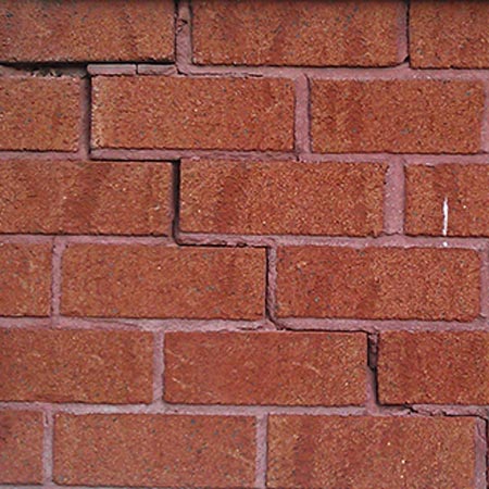 Mur de briques fissurés ayant besoin de réparations et entretien